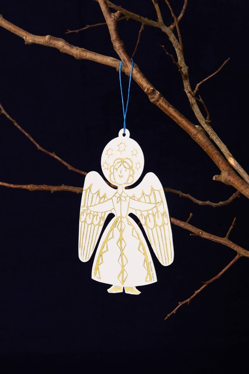 Decorative angel ornament hanging from a branch against a dark background