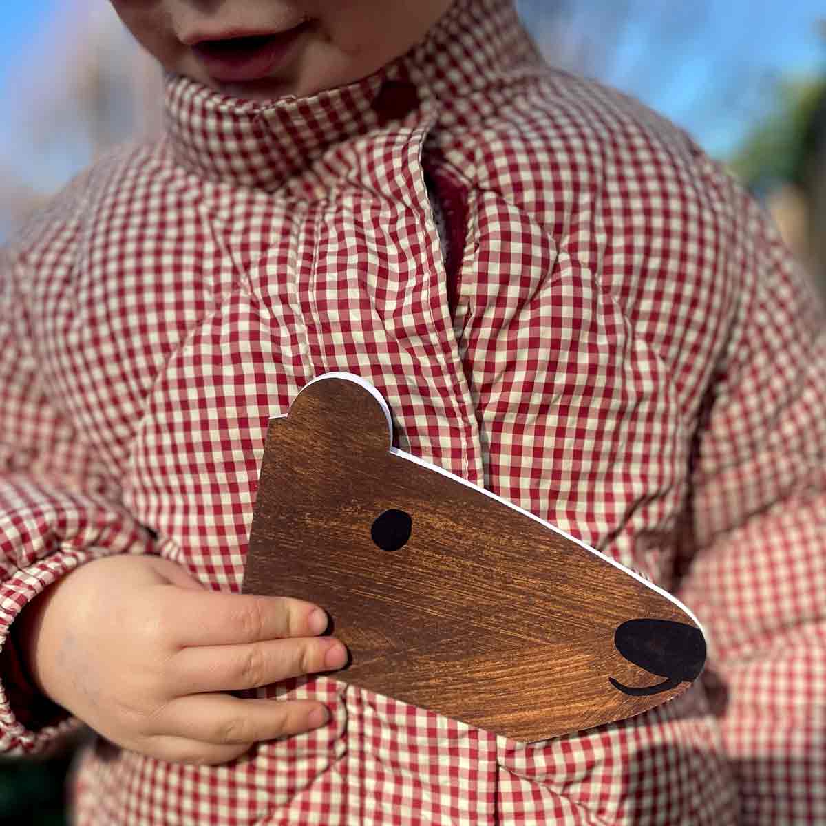 Bestselling brown Bear shaped card held in child hand against gingham jacket