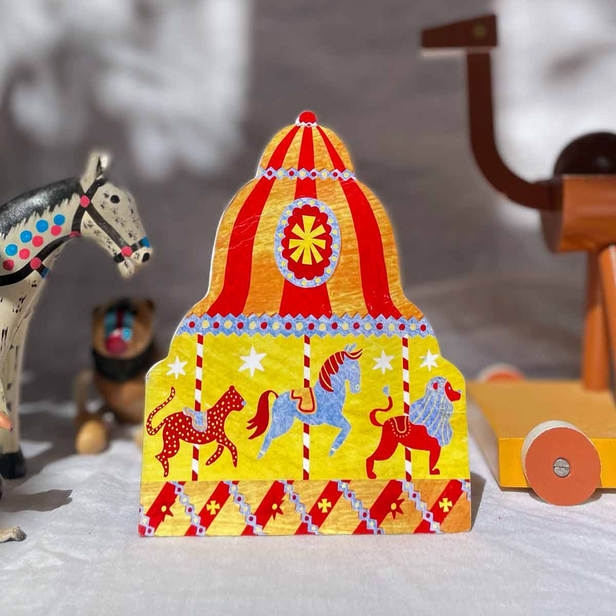 Eco friendly carousel shaped greeting card surrounded by wooden toys