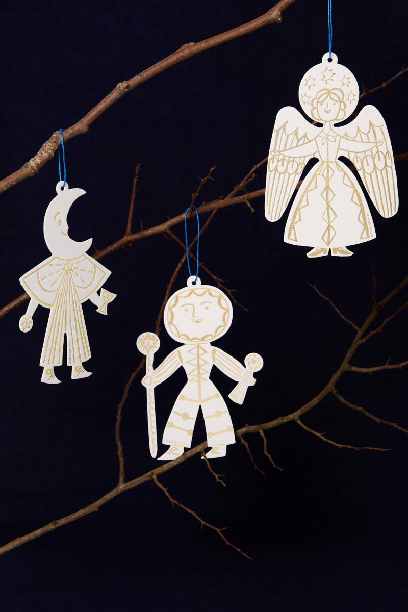 Decorative letterpress ornaments of celestial figures hanging on a branch against a dark background