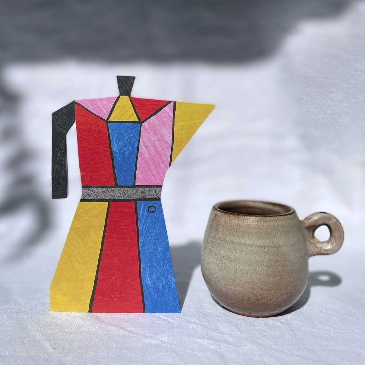 Colourful post-modern coffee pot shaped card one a white cloth background