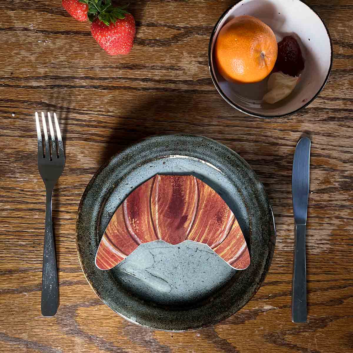 Croissant shaped card on a plate on a kitchen table with breakfast foods