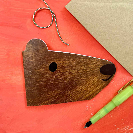 Beautiful minimalist brown bear shaped card on orange background with fountain pen