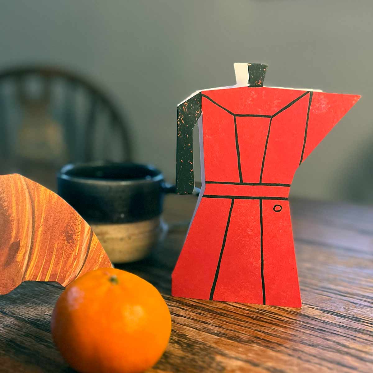 Coffee Pot shaped card on kitchen table with croissant card and orange