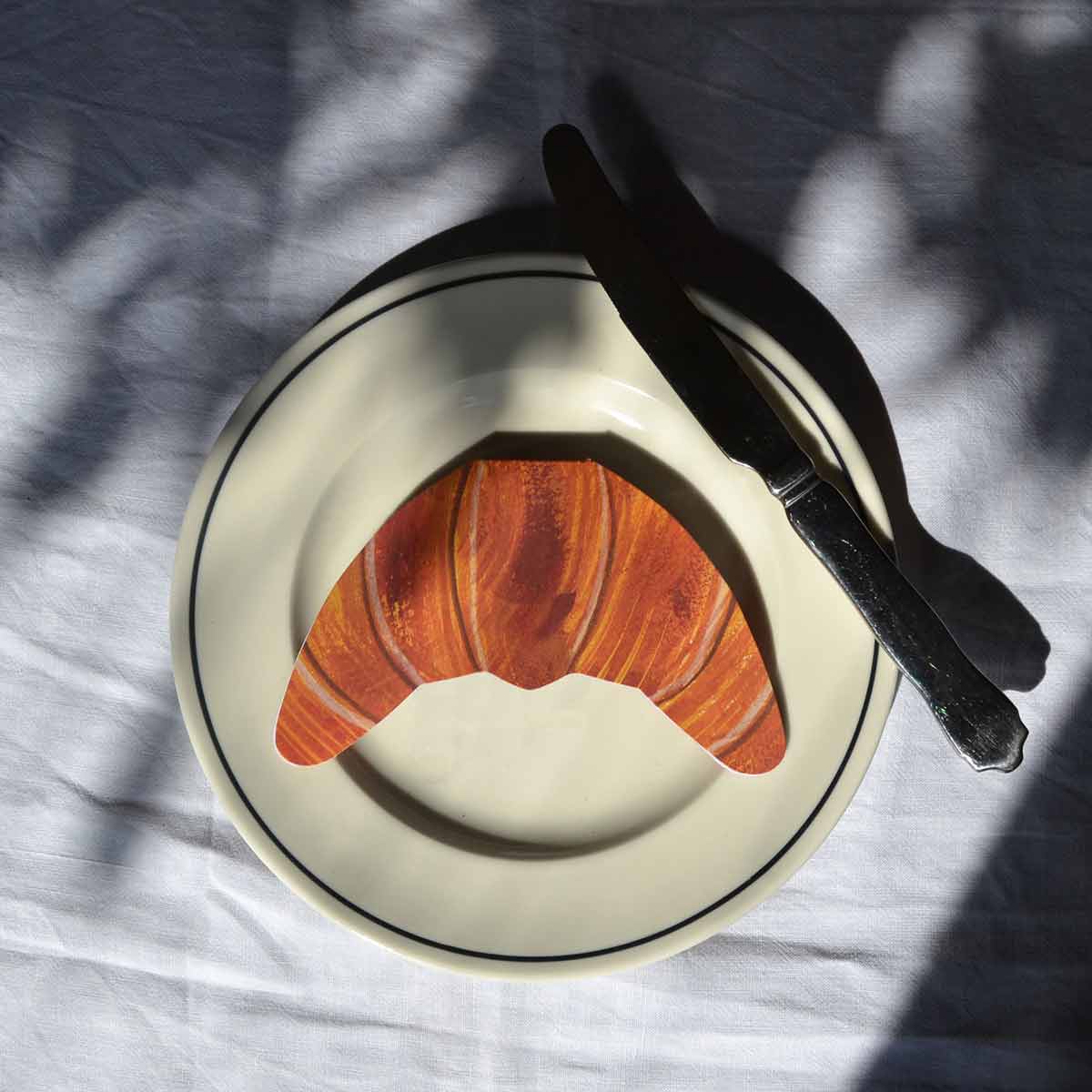croissant shaped card on plate on a white tablecloth