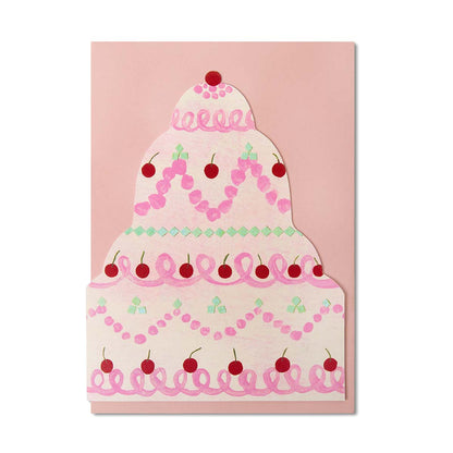 Illustrated tiered birthday cake shaped greetings card with looped icing and red cherries on a blush pink envelope.