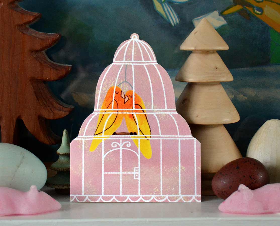 Pink card with two lovebirds in a white cage snuggled together