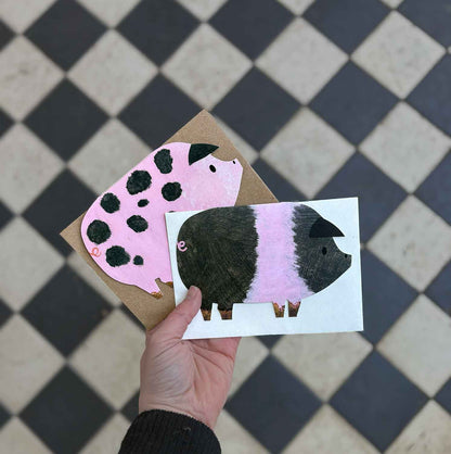 Hand holding a two pig cards against a checkered floor background