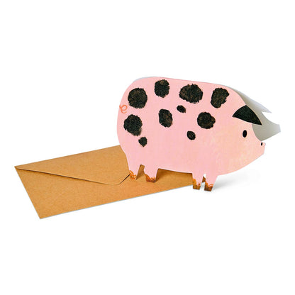 Pink spotty pig-shaped greetings card on a white background with brown recycled envelope