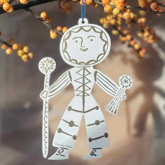 Decorative sun folk gold and cream hanging decoration hanging against a blurred natural background.